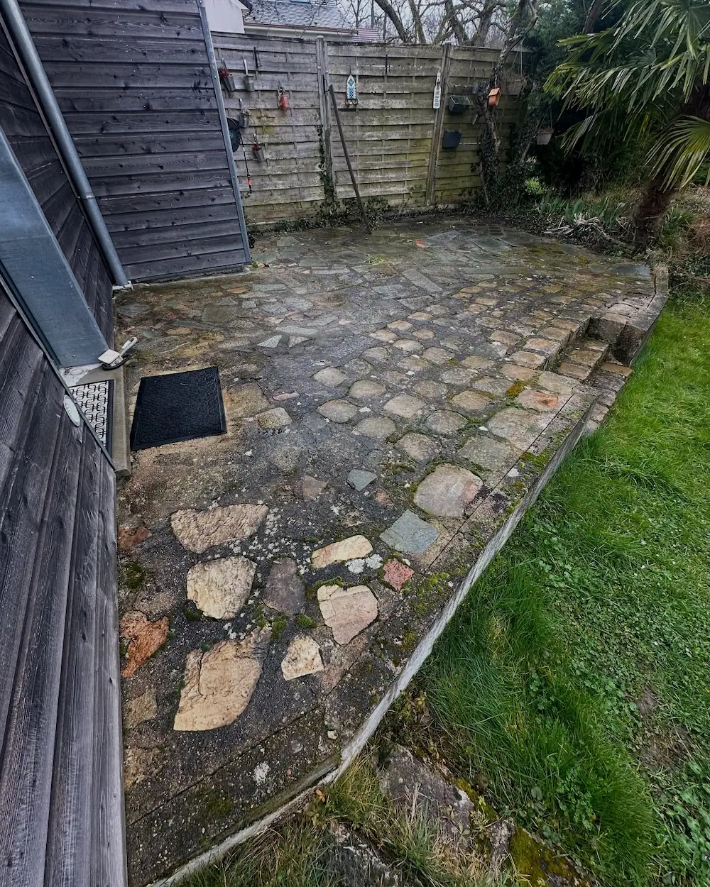 Ancienne terrasse en pavés irréguliers et dégradés avant les travaux de rénovation et la pose du travertin.