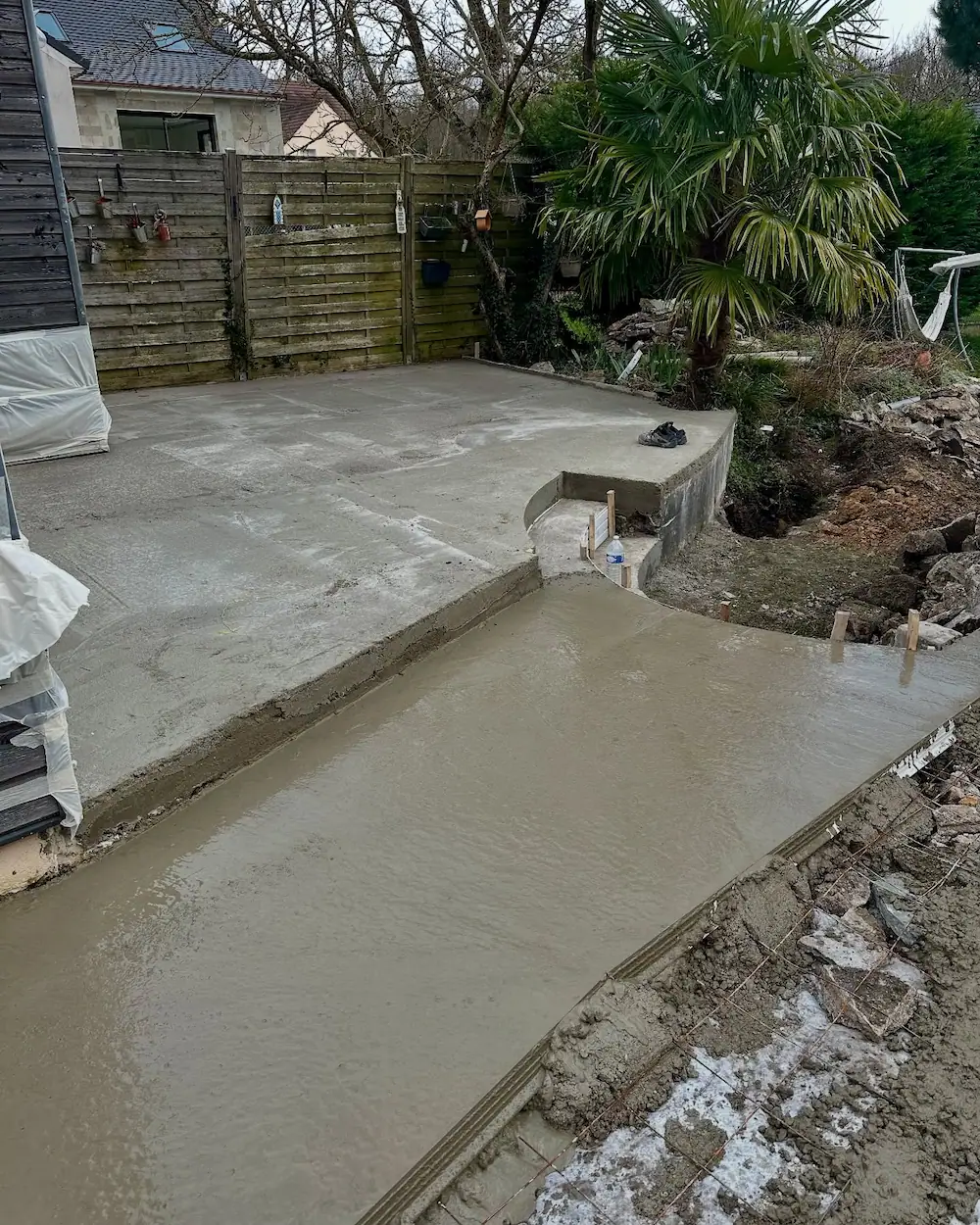 Coulage d’une dalle en béton pour préparer la future pose du revêtement en travertin sur la terrasse.